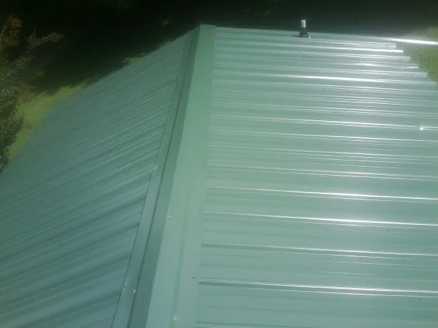 New green metal panels meeting at the ridge of a roof — Flat Roof Repair work by our crew in Spring City